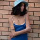 Portrait shot of model wearing the Saturday Bucket Hat – Blue. Lightweight cotton chenille with wide brim, breathable cotton inner band, and UPF 50+ rating. A bright unisex summer essential for festivals, beach days, and streetwear styling.