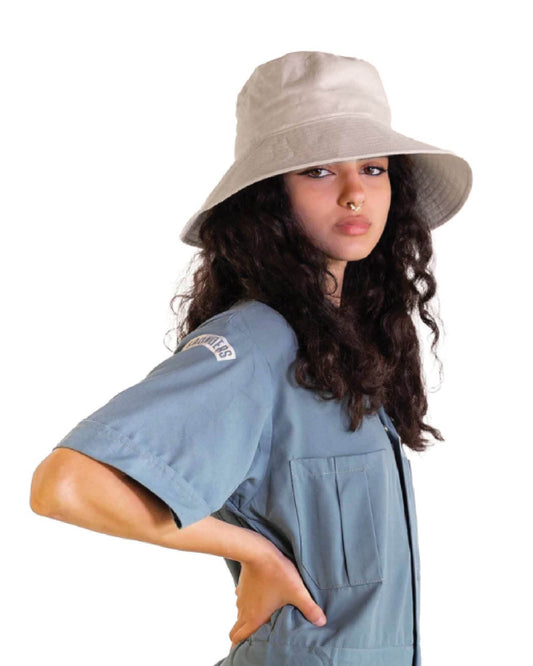 A female model wearing The Sandbar in natural linen, styled with a relaxed denim shirt. The image captures the soft drape of the hat’s semi-floppy brim and minimalist design, suited to sun protection and everyday wear. A lightweight staple from the bucket hats collection.

