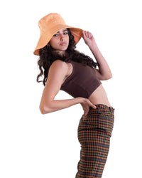 Model wearing The Sandbar peach linen bucket hat, styled with a brown crop top and patterned pants. The hat’s wide brim and natural drape offer a flattering silhouette while providing practical sun protection. A relaxed look for summer styling.

