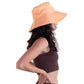 Side view of a model in The Sandbar peach linen hat, showing the floppy shape and longer brim. Perfect for long beach walks or slow afternoons outdoors, this piece blends vintage-inspired style with modern comfort in a lightweight, breathable fabric.

