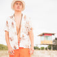 Full-body portrait of model wearing Saturday Bucket Hat – White by FallenBROKENstreet. Lightweight cotton chenille hat with wide brim and UPF 50+ protection. Styled casually with floral shirt and shorts, photographed by the coast, emphasising its travel and summer-ready versatility.