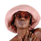 Woman wearing The Sunday pink foldable bucket hat from FallenBROKENstreet with rose sunglasses, styled for summer comfort and effortless cool.

