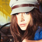 Model wearing The Sea Cap – Steel by FallenBROKENstreet, styled with deep blue sweater in vintage car interior. Canvas sailor cap with leather band and ocean-inspired detailing.