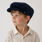 Young boy wearing a navy cap against a plain background
