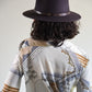 Person wearing a dark hat and patterned shirt with a plain background