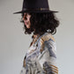 Woman wearing a patterned shirt and black hat against a plain background