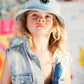 Person wearing a denim vest and cap with a colorful background