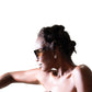 Female model with short hair poses in The Cosmos – Moondust/Amber sunglasses. Captures fashion-forward attitude, amber lenses and bold acetate frame in a clean minimalist setting.