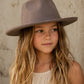 Young girl wearing a brown hat against a neutral background