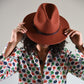 Woman wearing a rust coloured felt fedora