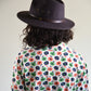 Person wearing a dark hat and a floral patterned shirt against a plain background