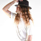 Person wearing a black hat and white t-shirt against a white background