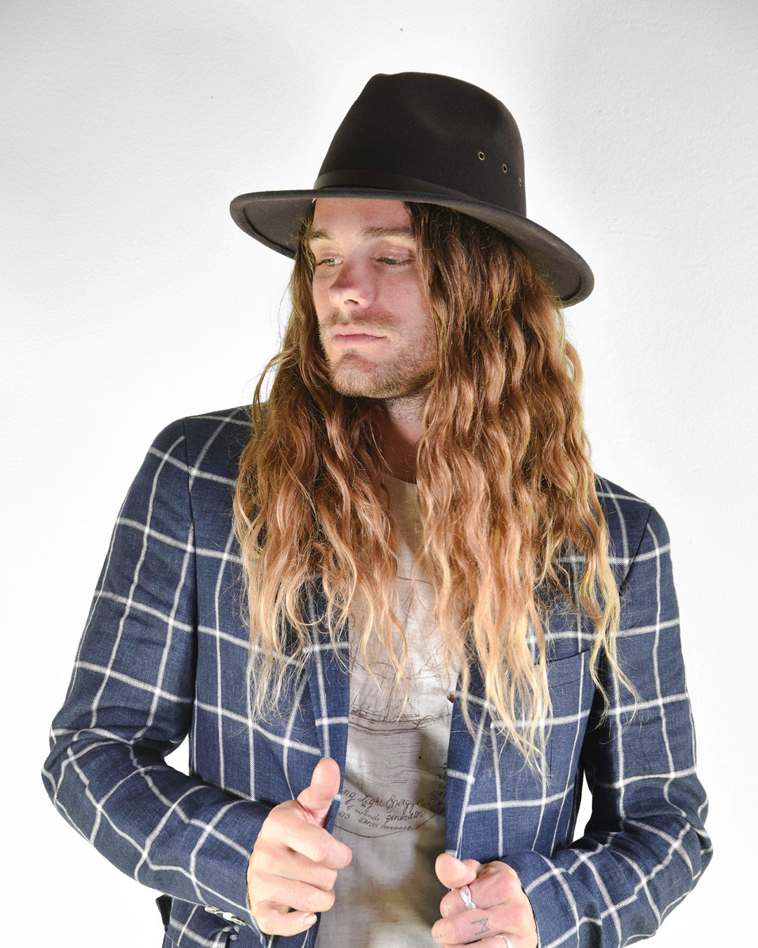 Man wearing a black hat and blue checkered jacket on a white background