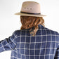 back view of a man in a blue coat wearing a wool felt hat in cream colour