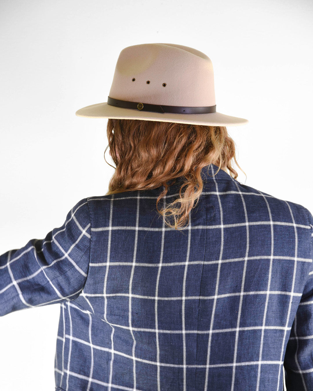back view of a man in a blue coat wearing a wool felt hat in cream colour