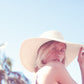 Person wearing a wide-brimmed hat against a clear blue sky