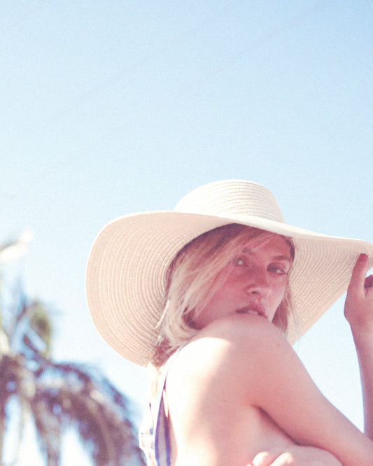 Person wearing a wide-brimmed hat against a clear blue sky