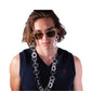 Editorial-style image of male model in sleeveless black top, showcasing the oversized acetate chain as a statement eyewear piece from Fallenbrokenstreet.

