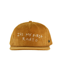 Mustard corduroy cap with white embroidered text "It’s My First Rodeo" on the front panel, featuring a flat brim and signature Fallenbrokenstreet button on the side.