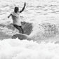 A surfer rides a wave in Byron Bay wearing the Surf Stash Cap by FallenBROKENstreet. Captured in black and white, the image reflects coastal lifestyle and freedom, with the hidden stash pocket design perfect for travel and festivals. The Surf Stash Cap – Red combines surf culture with timeless streetwear style for beach days and beyond.