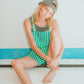 Model in striped green overalls sitting and smiling while wearing the Dope Lemon dad cap.

