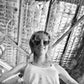 Grainy black-and-white image of a woman standing beneath corrugated roofing wearing The Astral Plane sunglasses. A candid, artistic atmosphere that contrasts the sleek glasses design.

