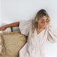 Natural light portrait of the model seated on a cushion, resting her head on her hand while wearing The Astral Plane Pink/Pink

