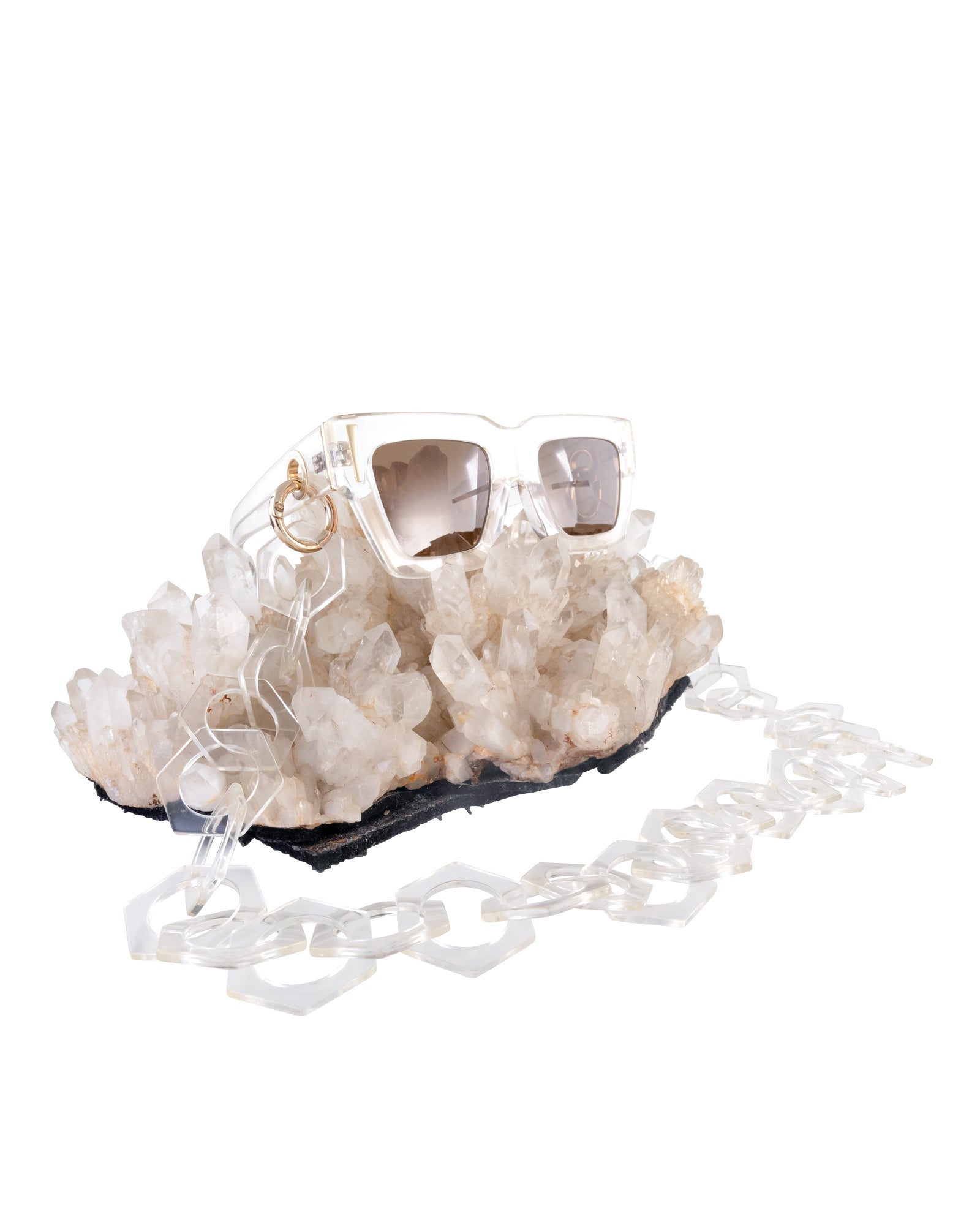 Sunglasses resting on natural quartz with visible gold accents and amber lenses. Elegant, earthy styling showcasing Fallenbrokenstreet details.

