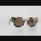 Video preview of The Cosmos – Moondust/Amber sunglasses rotating on white background. Helps customers experience the product in motion, highlighting chain loops, lens tint, and finish.