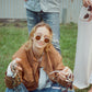 On-ground seated image of model in Skywalker/Amber sunglasses. Smiling with friends, capturing carefree vibe and laid-back attitude. Highlights real-life styling and comfort fit of the shades.