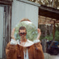 Model wears The Mischief – Galaxy/Pink sunglasses with a faux fur coat and headscarf, styled in a retro-inspired outdoor scene. Captures the playful, artistic vibe of the collection.

